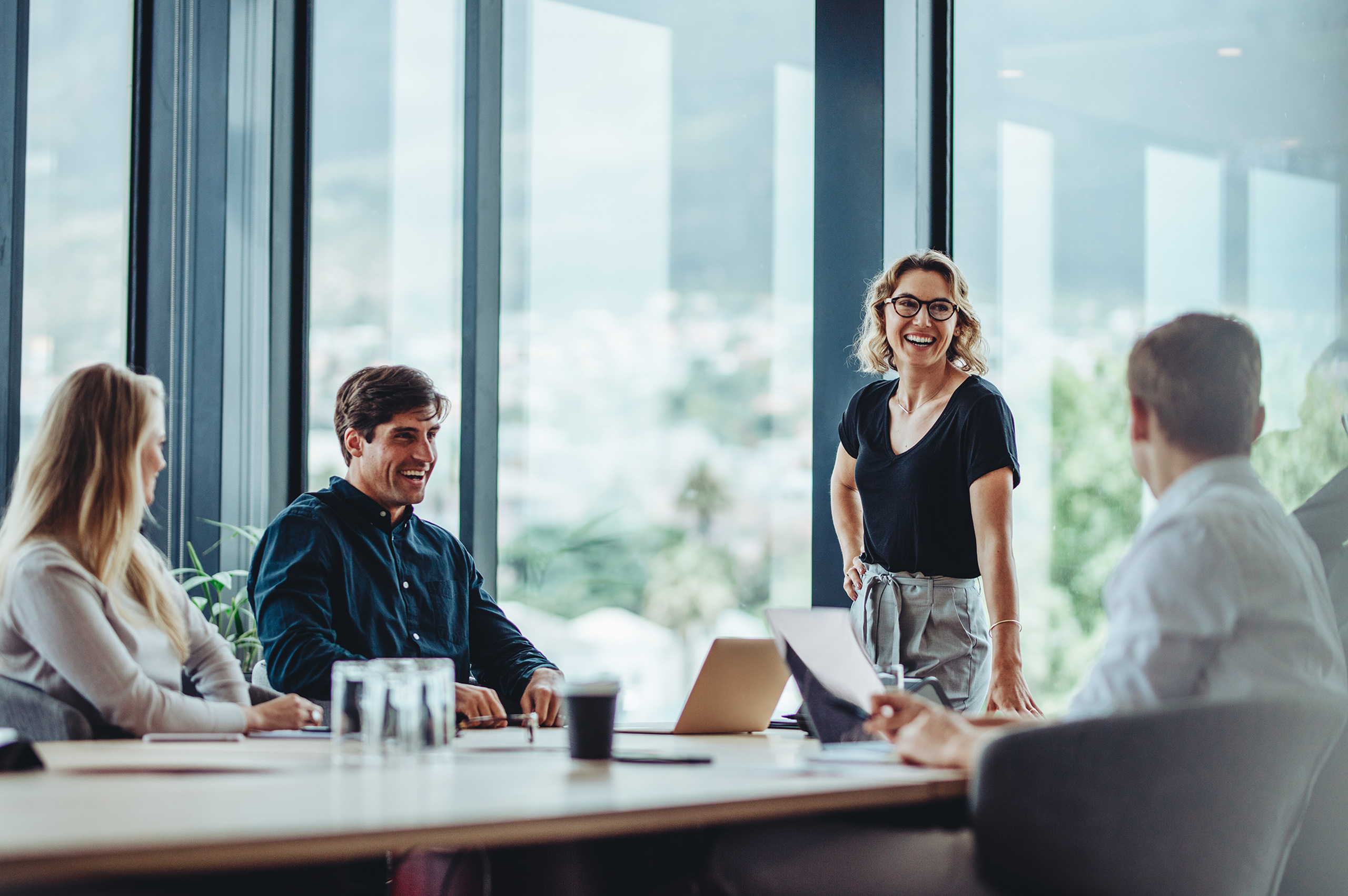 Office colleagues having casual discussion during meeting in conference room. Group of men and women sitting in conference room and smiling.